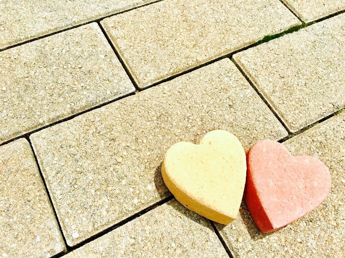 石畳の上に並べられた黄色と赤色のハート形のオブジェ